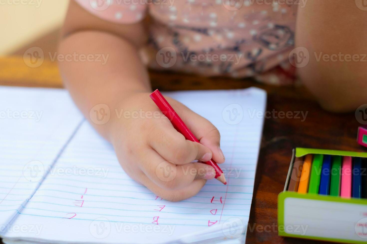 primo piano della mano della ragazza con la matita che scrive parole inglesi a mano foto