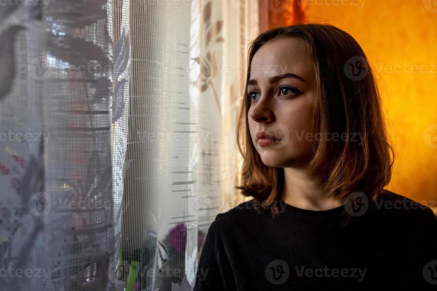 ritratto di una giovane ragazza adolescente in una stanza vicino alla finestra la sera foto