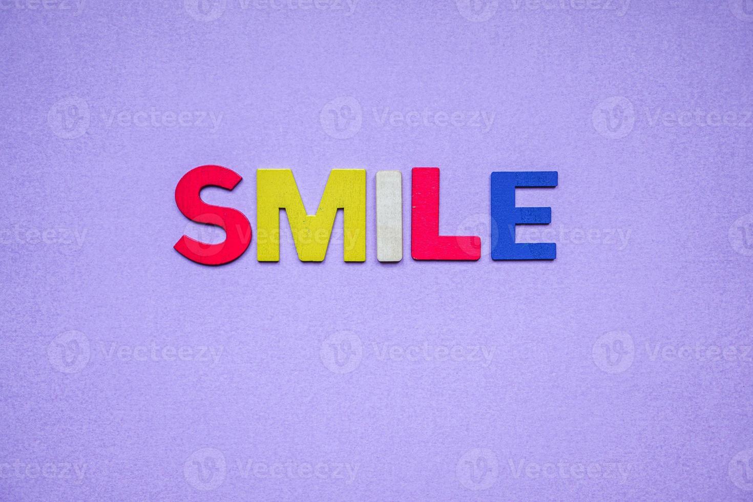 parola sorriso con lettere in legno sullo sfondo viola foto