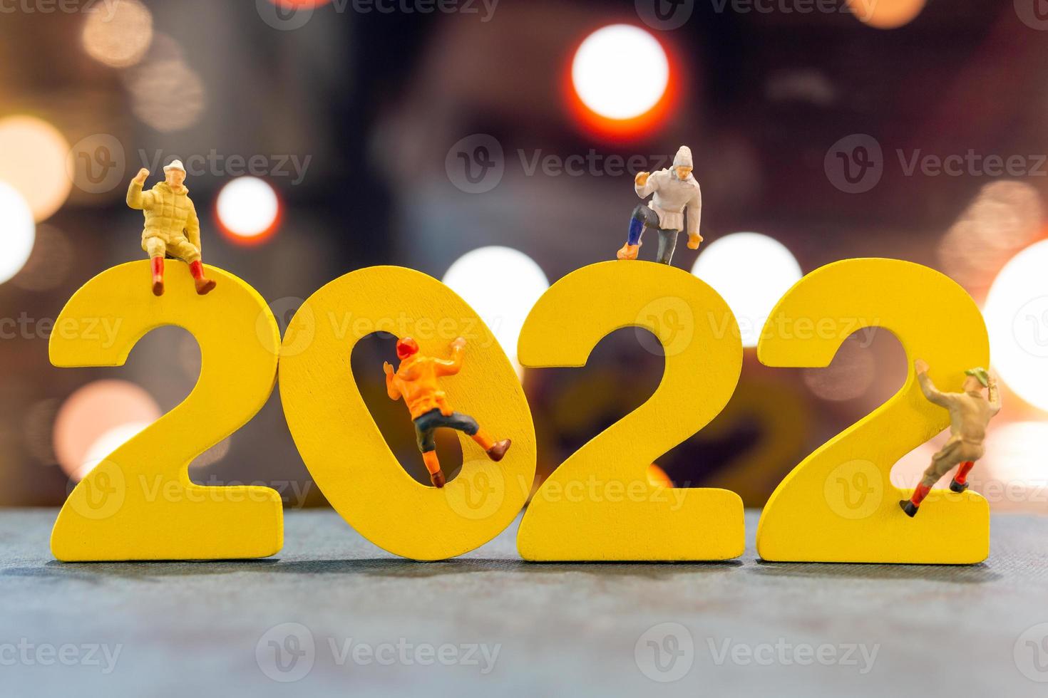 persone in miniatura che si arrampicano su legno con il numero 2022 foto