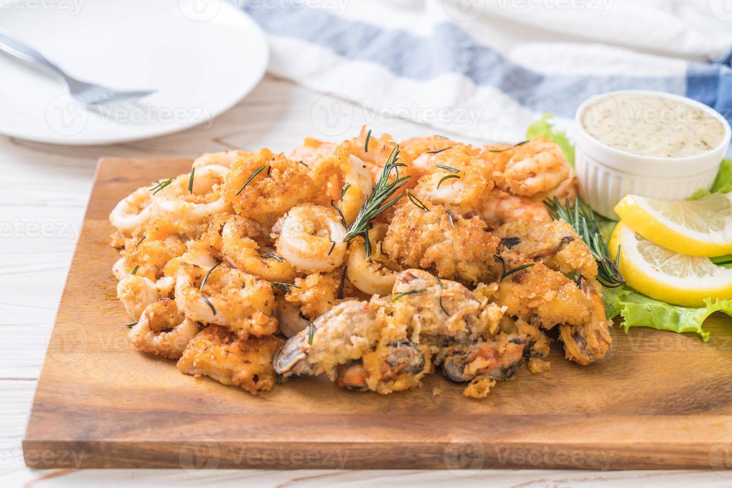 frittura di mare di calamari, gamberi, cozze con salsa su tavola di legno foto