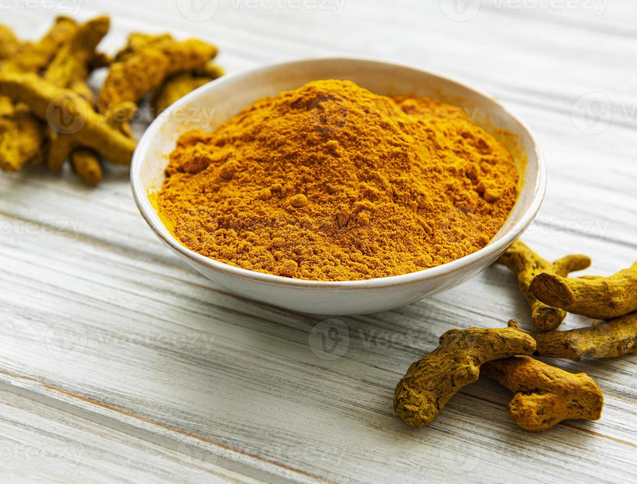 ciotola con polvere di curcuma e radici foto