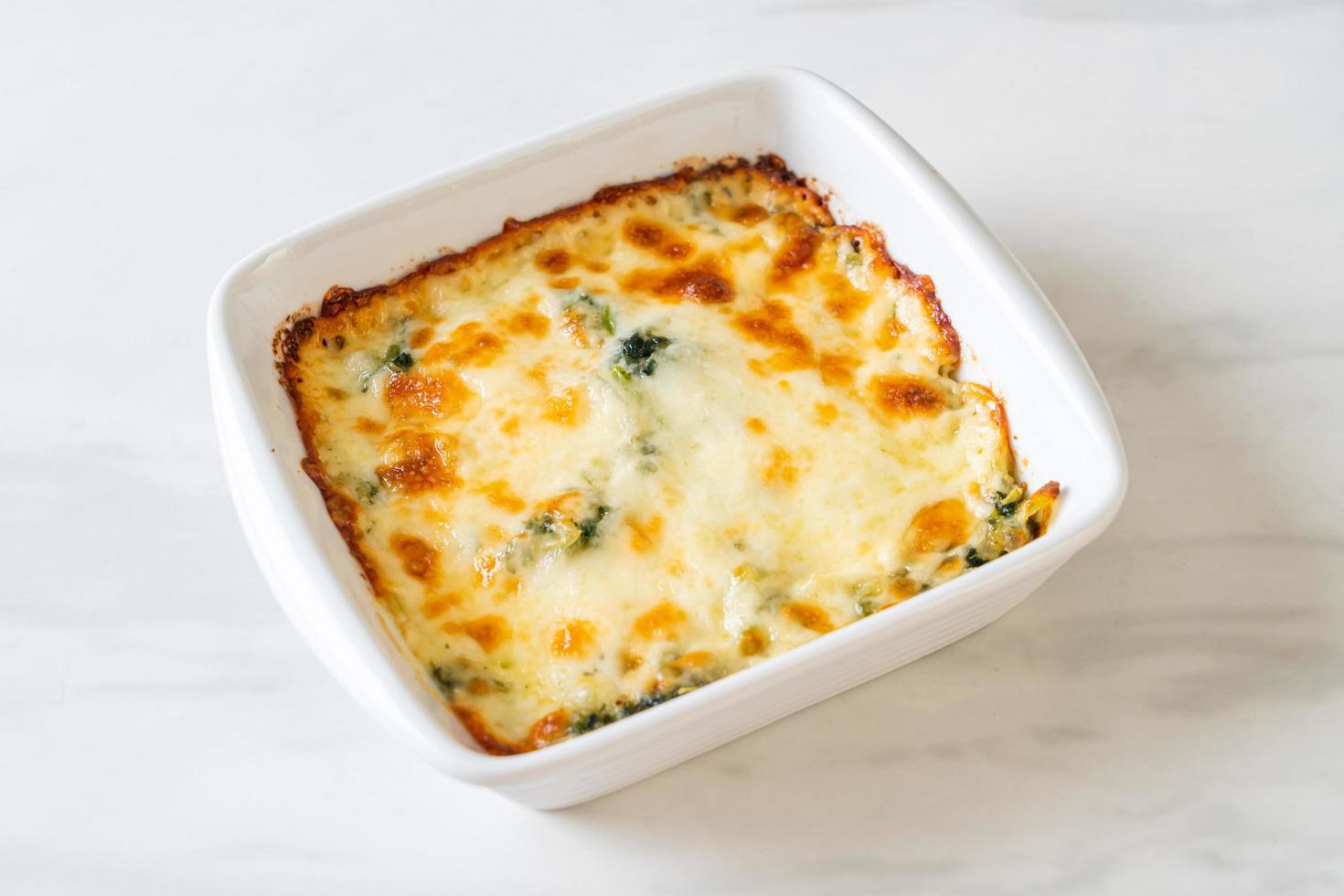 lasagne di spinaci al forno con formaggio in piatto bianco foto