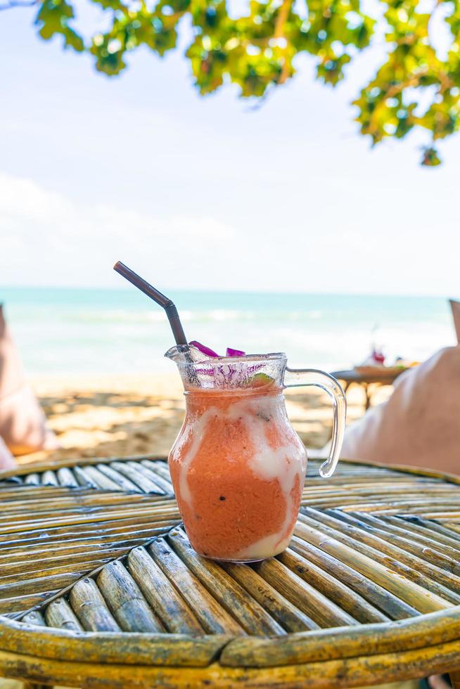 barattolo di frullati di mango, ananas, anguria e yogurt o yogurt con sfondo di spiaggia di mare foto