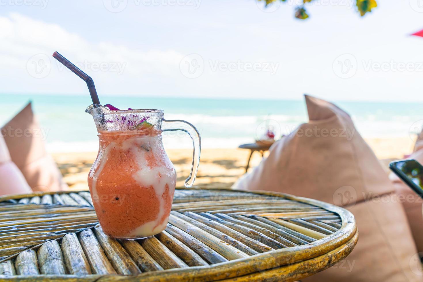 barattolo di frullati di mango, ananas, anguria e yogurt o yogurt con sfondo di spiaggia di mare foto