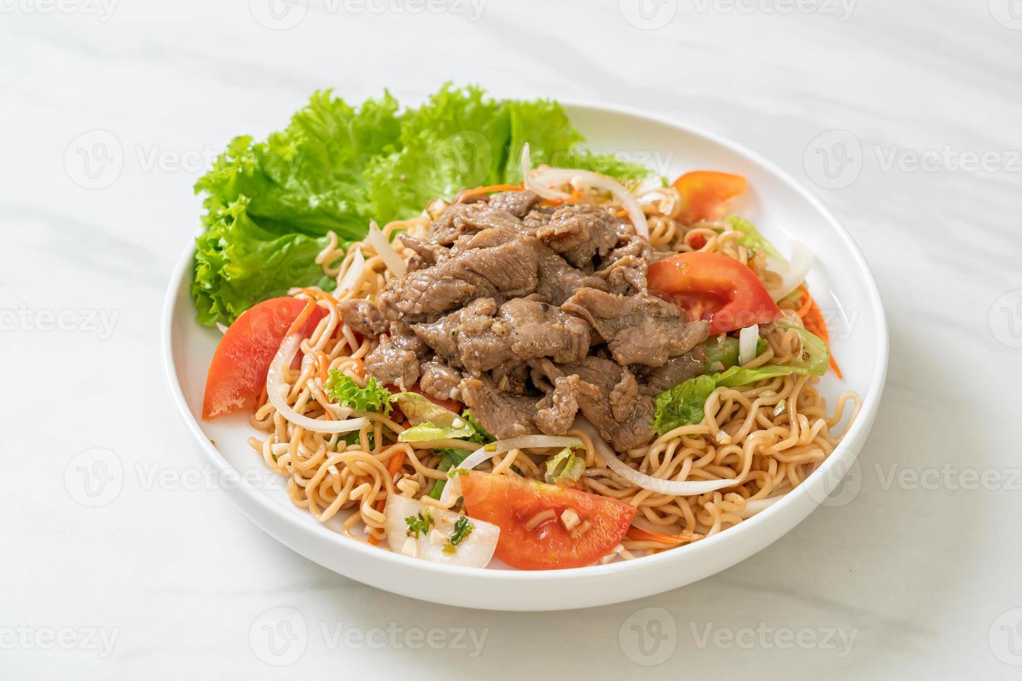 Insalata piccante di noodle istantanei con carne di maiale su piatto bianco - stile cibo asiatico foto