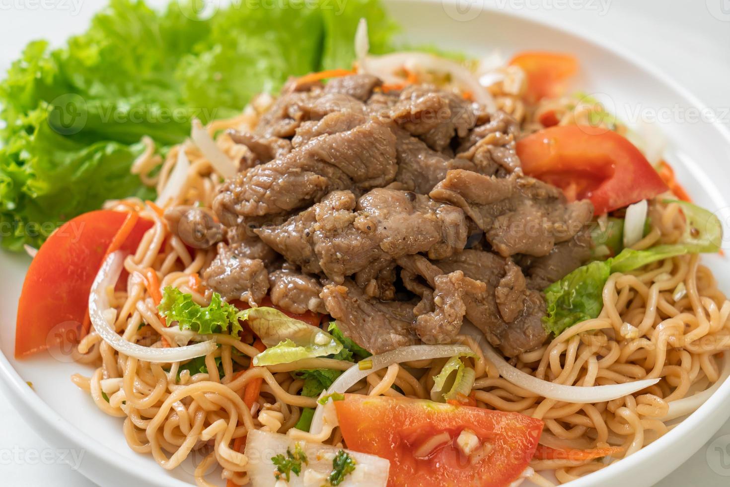 Insalata piccante di noodle istantanei con carne di maiale su piatto bianco - stile cibo asiatico foto