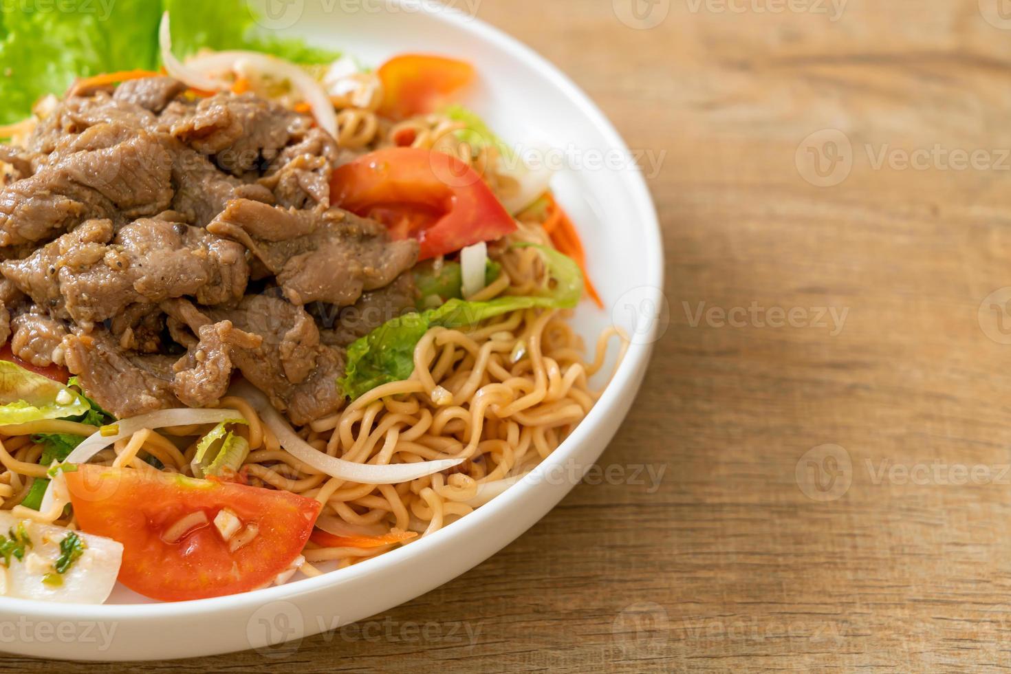 Insalata piccante di noodle istantanei con carne di maiale su piatto bianco - stile cibo asiatico foto