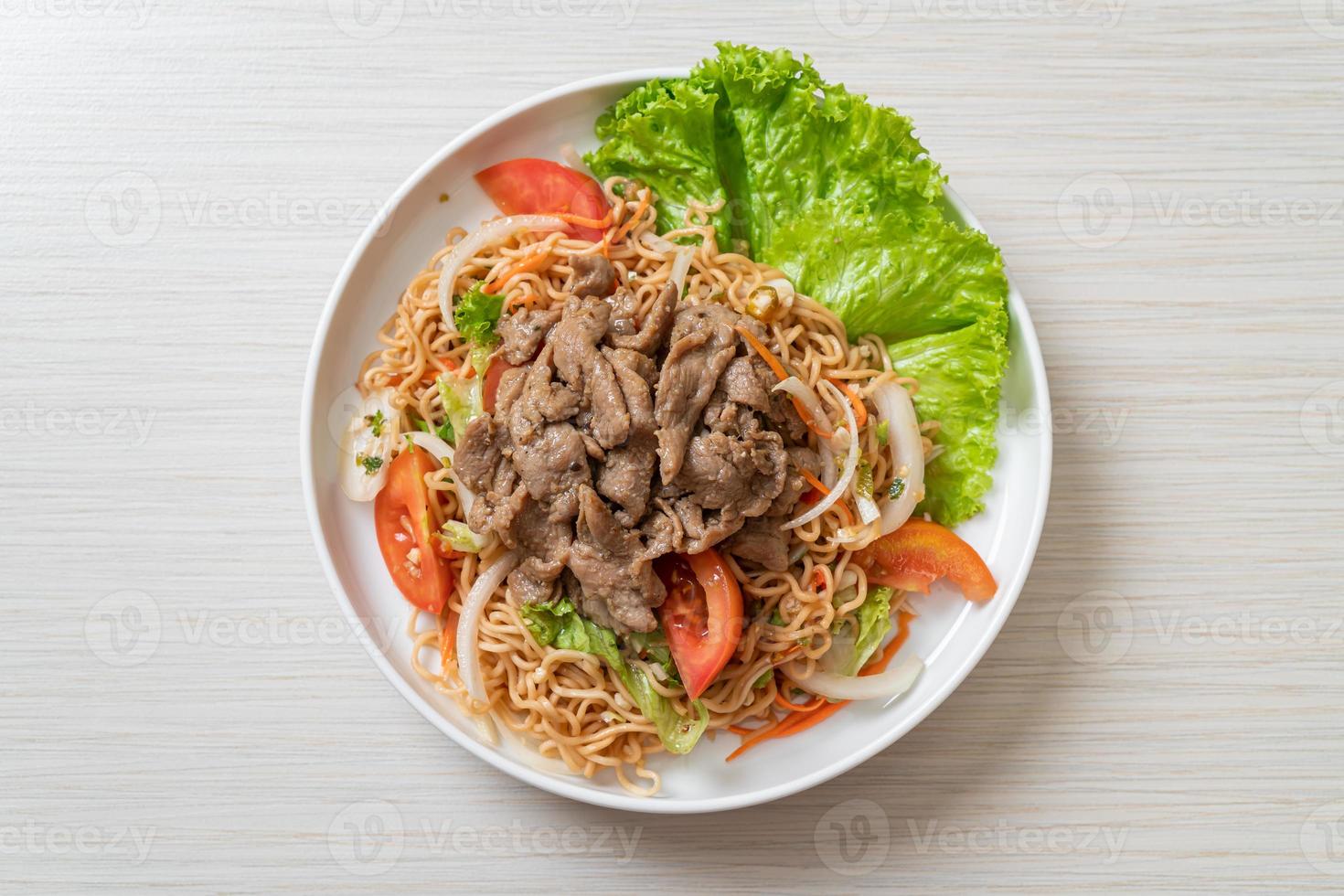 Insalata piccante di noodle istantanei con carne di maiale su piatto bianco - stile cibo asiatico foto