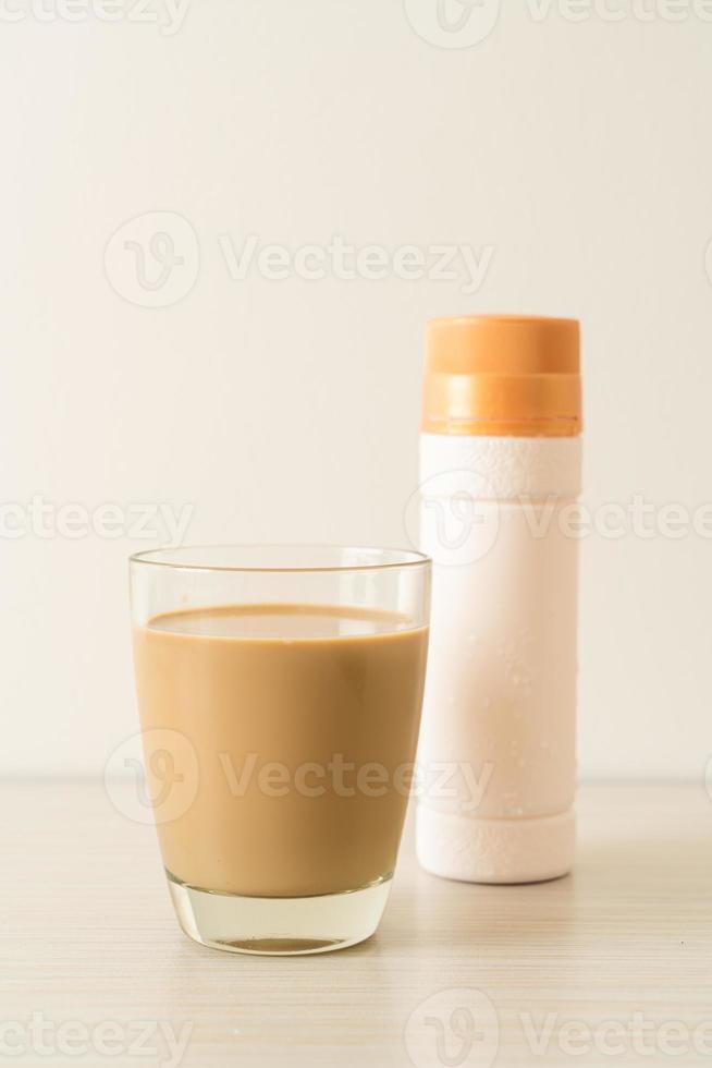 bicchiere di caffè latte con bottiglie di caffè pronte da bere sul tavolo foto
