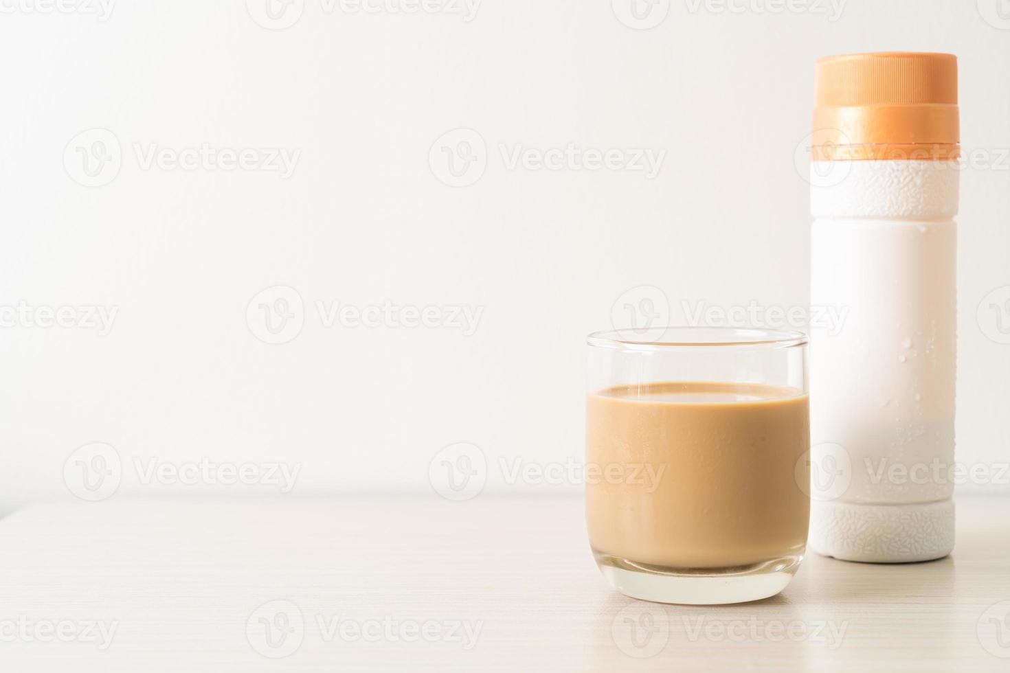 bicchiere di caffè latte con bottiglie di caffè pronte da bere sul tavolo foto