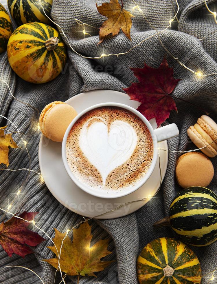 tazza di caffè, foglie secche e sciarpa su un tavolo foto