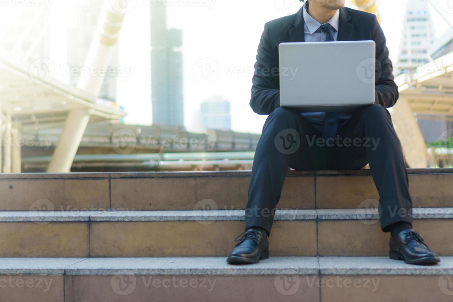 uomo d'affari seduto sulle orme con laptop foto