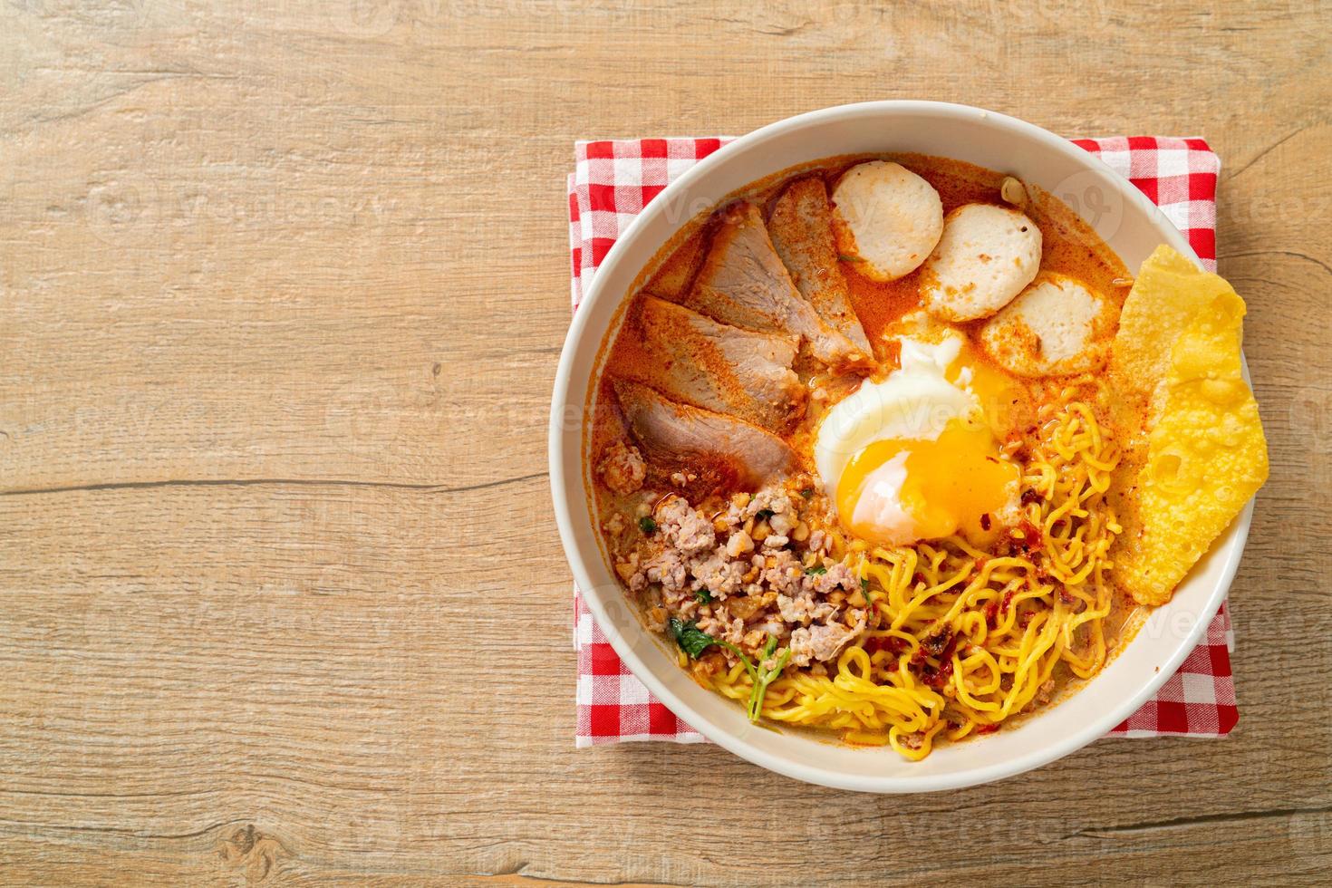 tagliatelle all'uovo con maiale e polpette in zuppa piccante o tagliatelle tom yum in stile asiatico foto