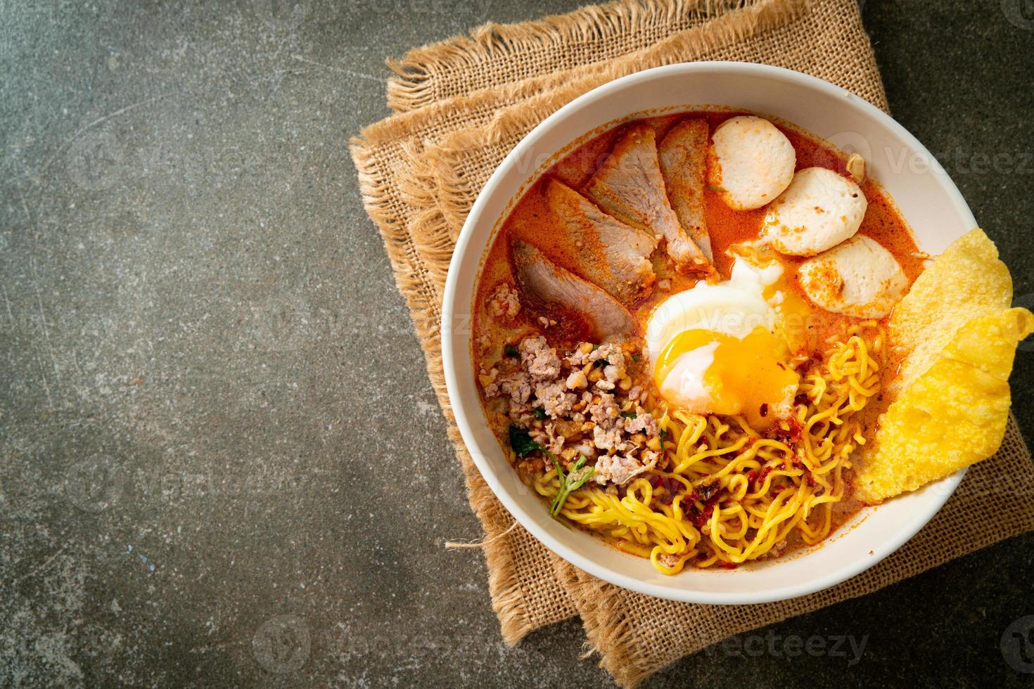 tagliatelle all'uovo con maiale e polpette in zuppa piccante o tagliatelle tom yum in stile asiatico foto