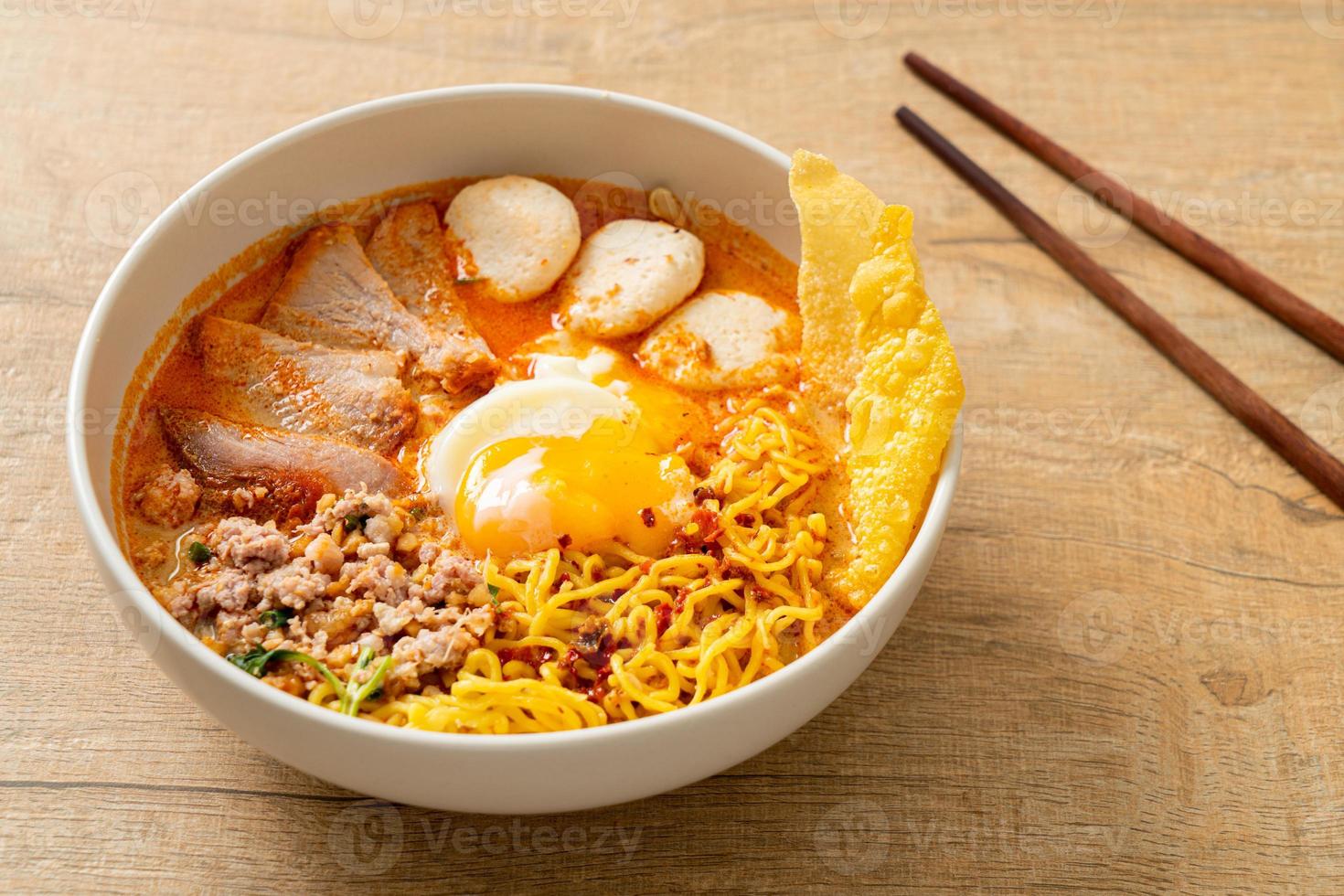 tagliatelle all'uovo con maiale e polpette in zuppa piccante o tagliatelle tom yum in stile asiatico foto