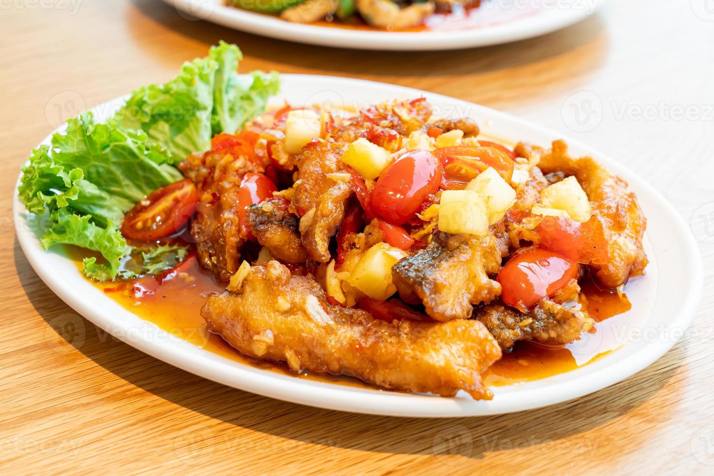 cernia fritta condita con salsa dolce, acida e piccante su piatto bianco - stile cibo asiatico foto