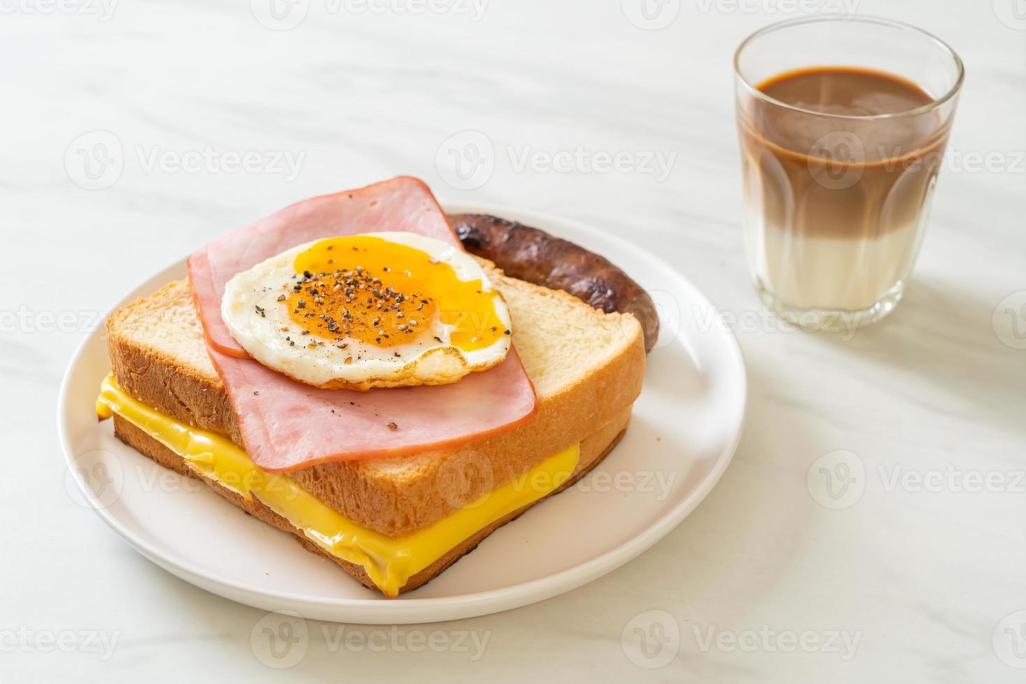 pane fatto in casa formaggio tostato condita con prosciutto e uovo fritto con salsiccia di maiale e caffè per colazione foto