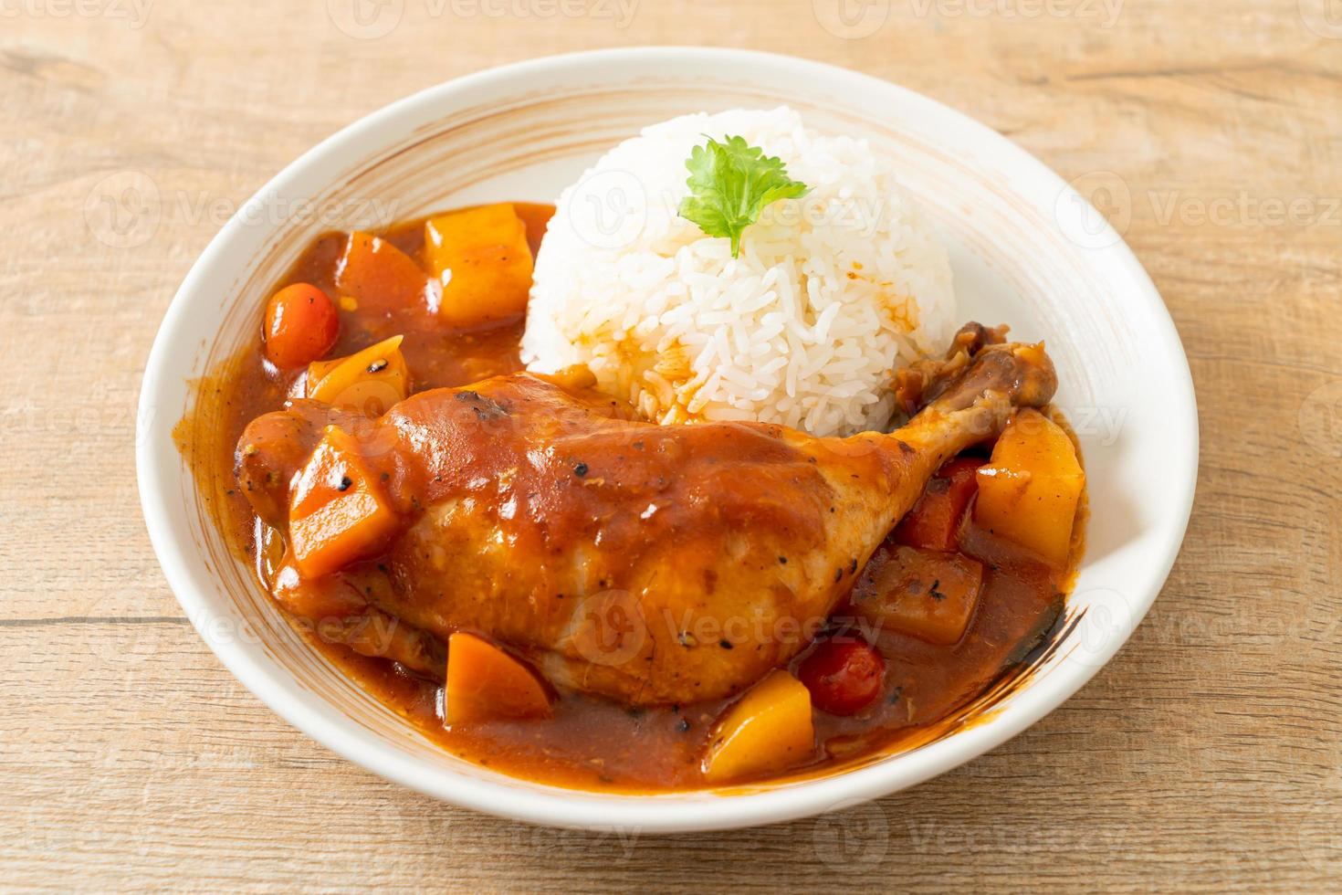 spezzatino di pollo fatto in casa con pomodori, cipolle, carote e patate su piatto con riso foto