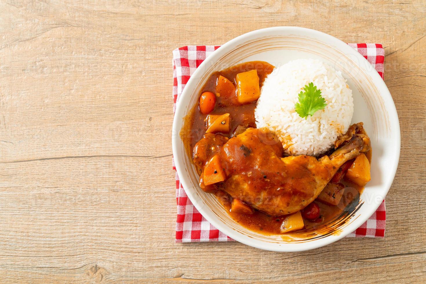 spezzatino di pollo fatto in casa con pomodori, cipolle, carote e patate su piatto con riso foto