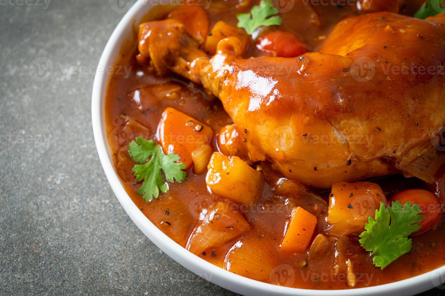 spezzatino di pollo fatto in casa con pomodori, cipolle, carote e patate su piastra foto