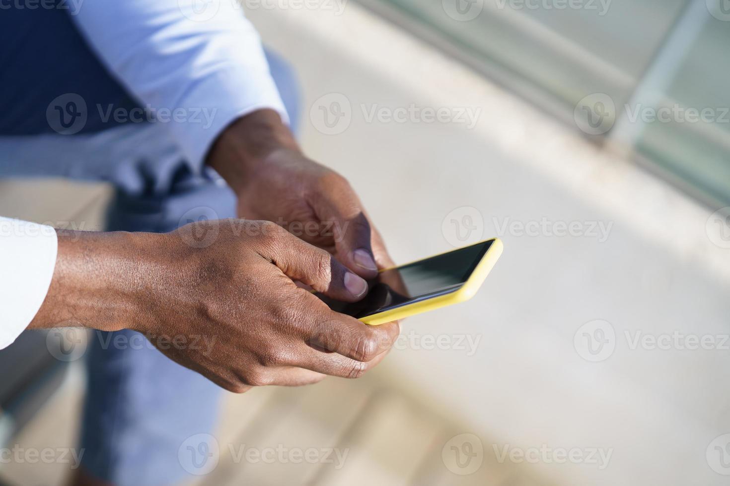 mani di un uomo di colore irriconoscibile che utilizza uno smartphone. foto