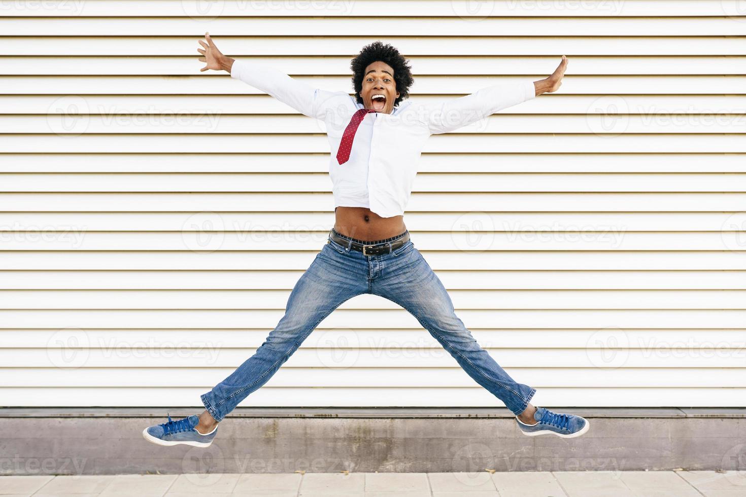 uomo d'affari nero che salta all'aperto. uomo con i capelli afro. foto