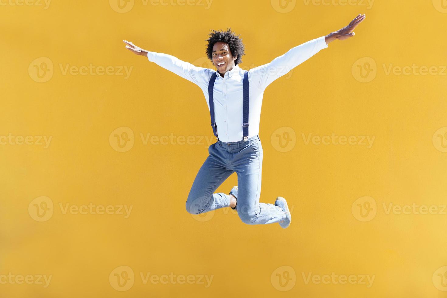 uomo di colore con capelli afro che salta su uno sfondo urbano giallo yellow foto