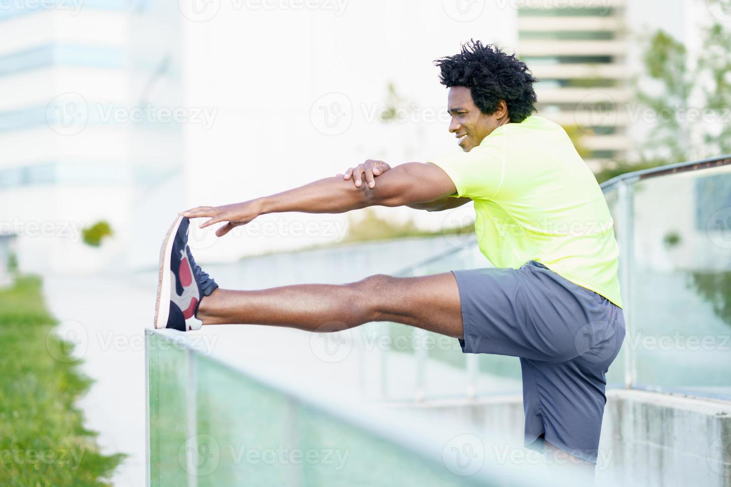 uomo di colore con i capelli afro che fa stretching dopo aver corso all'aperto. foto