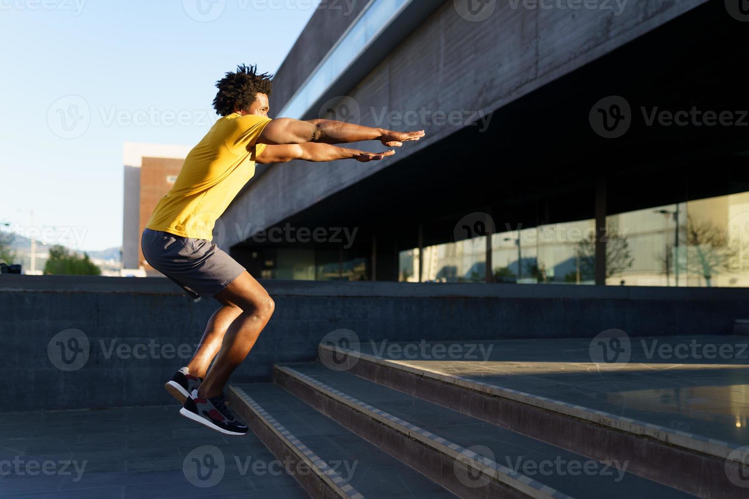 uomo di colore che fa squat saltando su un gradino. foto
