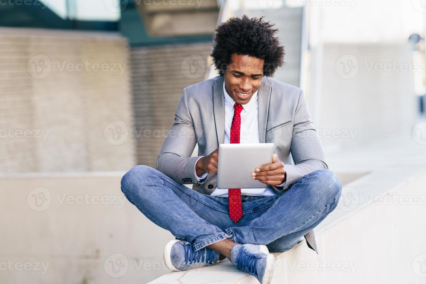 uomo d'affari nero che usa una tavoletta digitale seduta foto