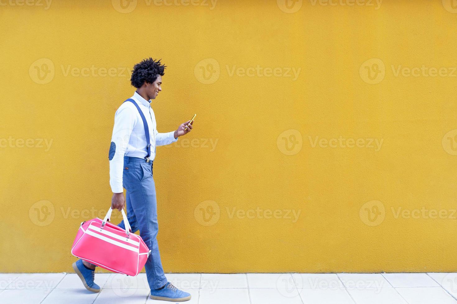 uomo di colore con acconciatura afro che porta una borsa sportiva foto