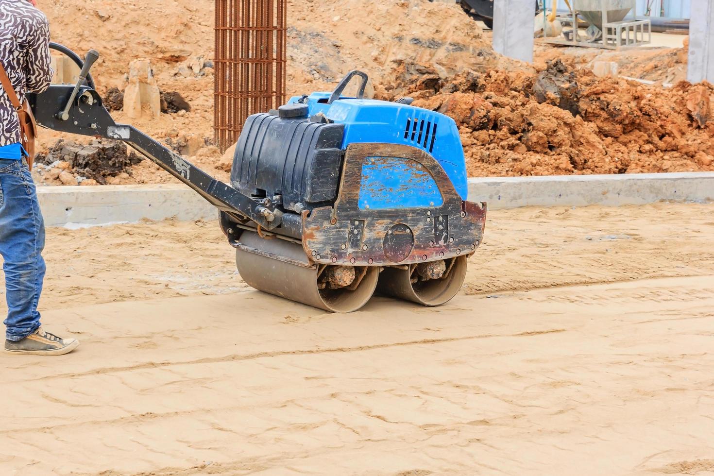 lavoratori durante il rullo compressore al lavoro sulla costruzione di strade foto