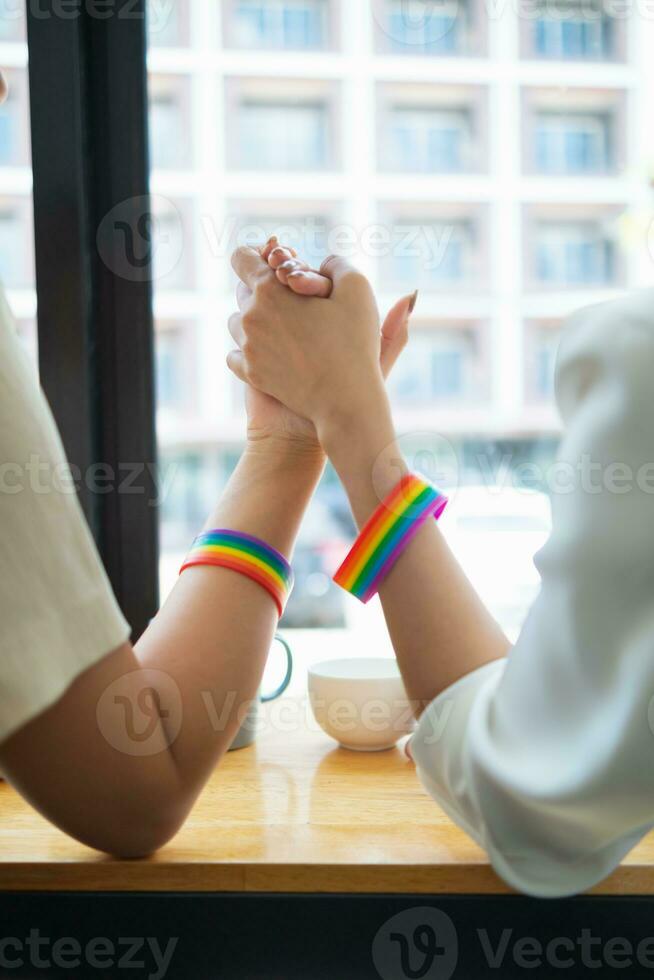 lgbt q coppia indossato arcobaleno braccialetti simboleggiante lgbt q gruppo e tenuto mani per mostrare amore, amicizia e gentilezza. e lgbt q coppia anche promesso per amore ogni altro per sempre. copia spazio per testo foto