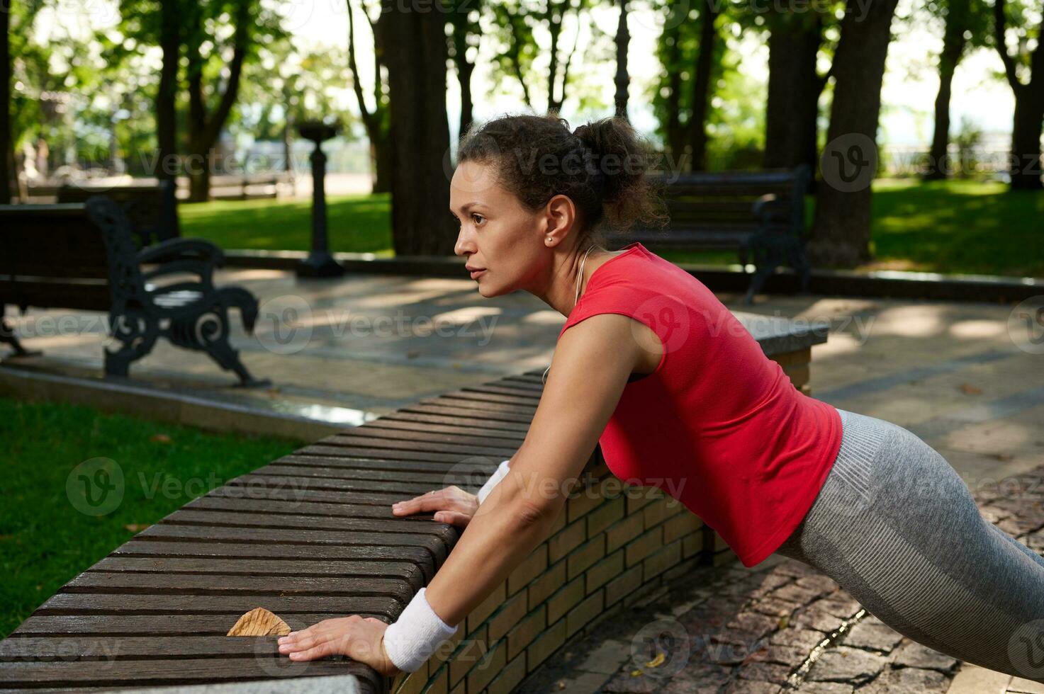 di mezza età attivo africano americano donna fare sollevamento su il città parco foto