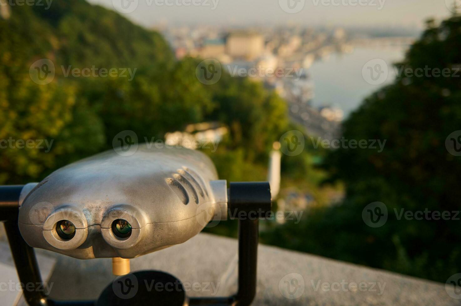 turista telescopio sembra a città con Visualizza di kiev e il dnieper fiume. avvicinamento vecchio metallo binoculare in piedi su un' collina con un' bellissimo Visualizza di il vecchio storico città. panoramico osservazione di natura foto