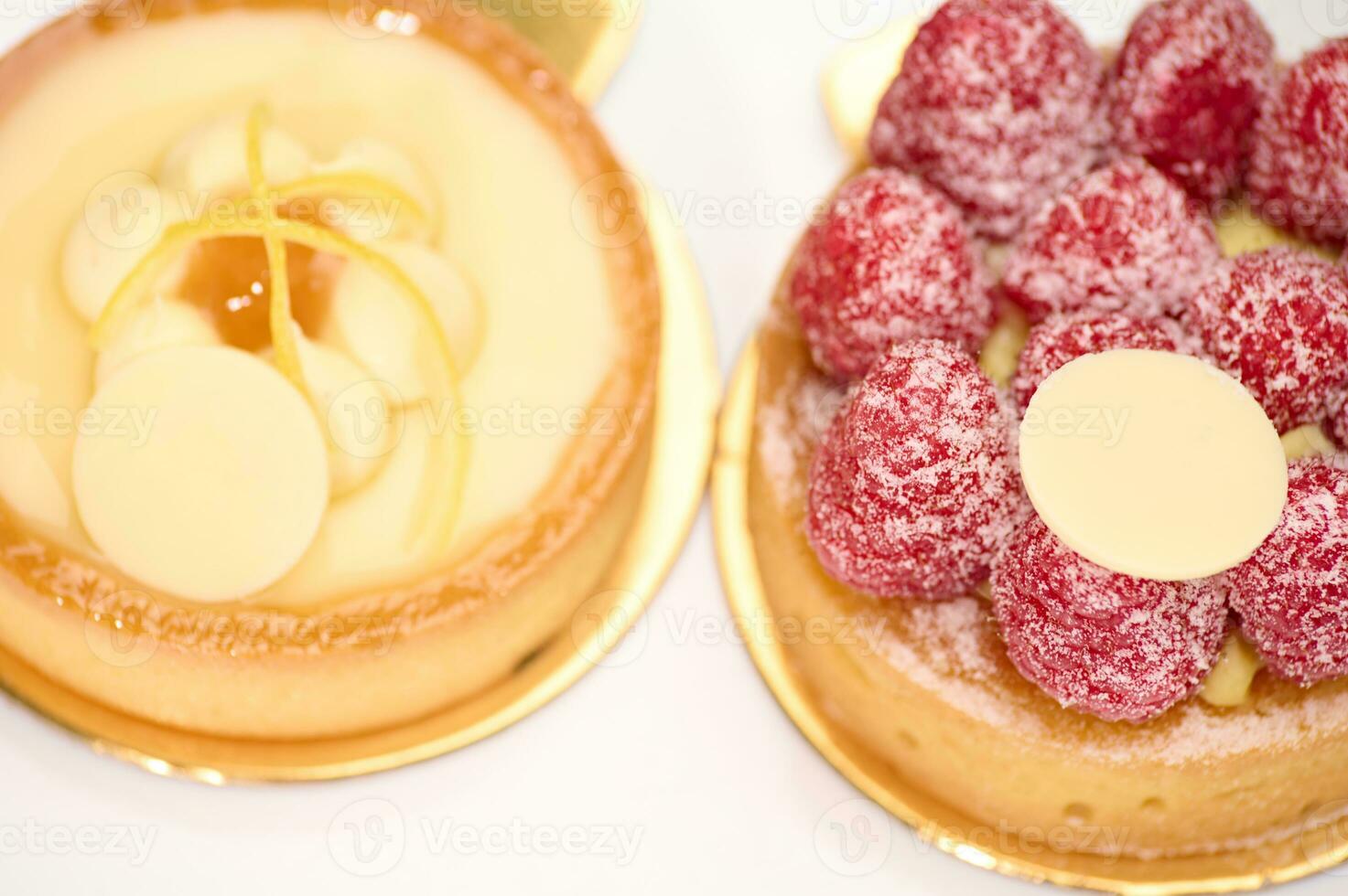 avvicinamento. alto Visualizza di francese dolci - un' Limone e lampone meringa torta e tortino su un' bianca piatto. foto