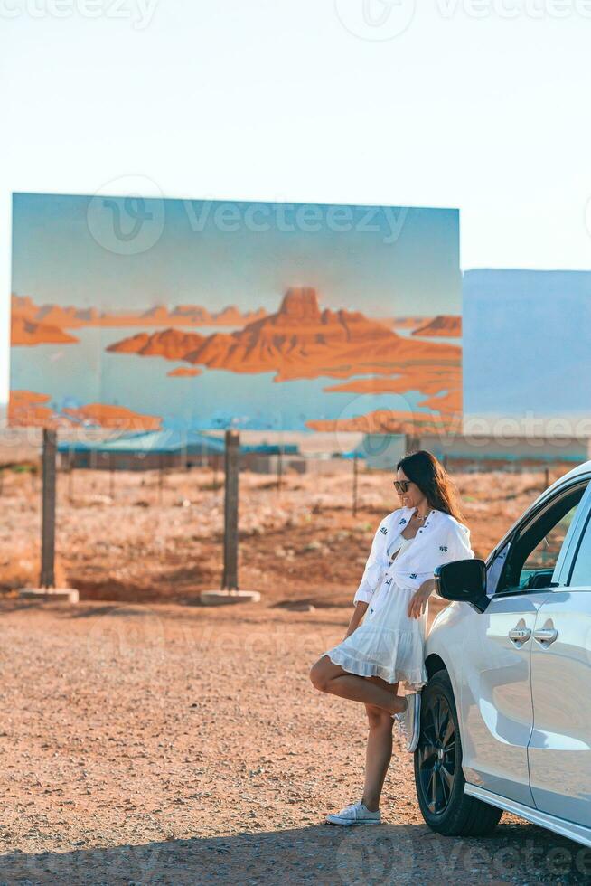 bellissimo donna su sua viaggio di il auto su il sfondo di benvenuto per Utah stato confine cartello giusto nel il monumento valle foto