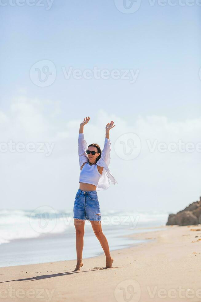 giovane contento donna su il spiaggia godere vento foto