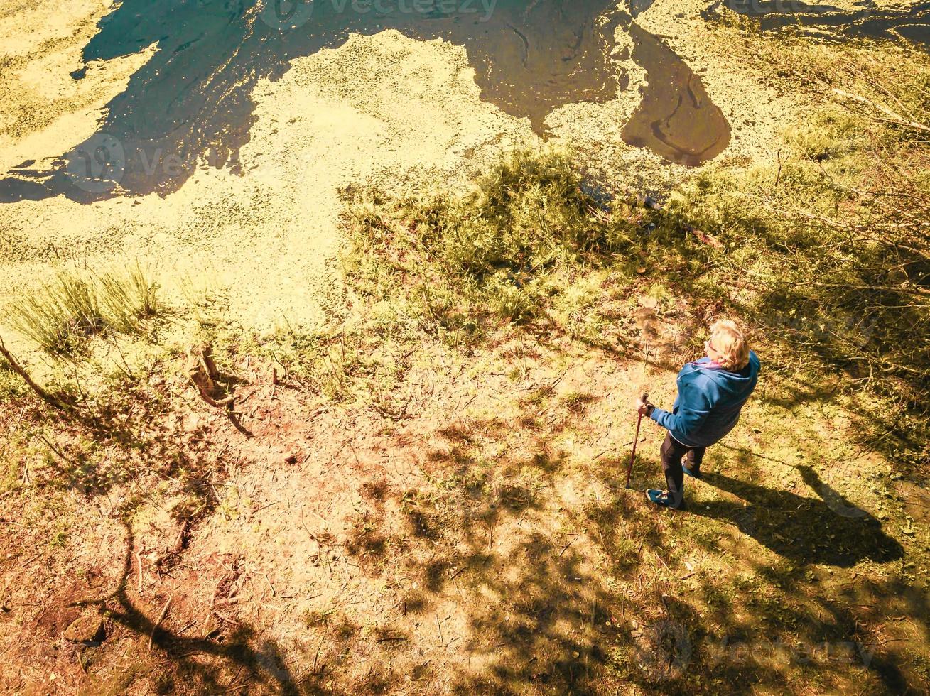 vista dall'alto in basso donna anziana in piedi con bastoncini nordici foto