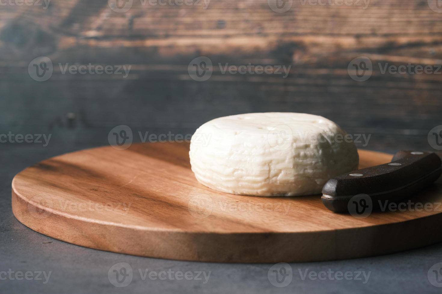 formaggio fresco di forma rotonda su un tagliere sul tavolo foto