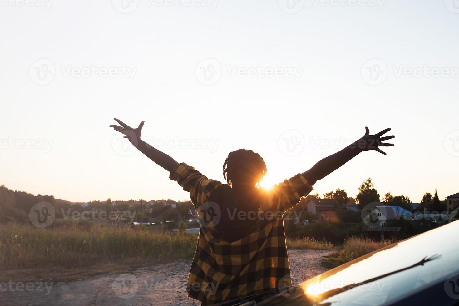la donna afroamericana felice vicino all'auto guarda il tramonto, lo stile di vita foto