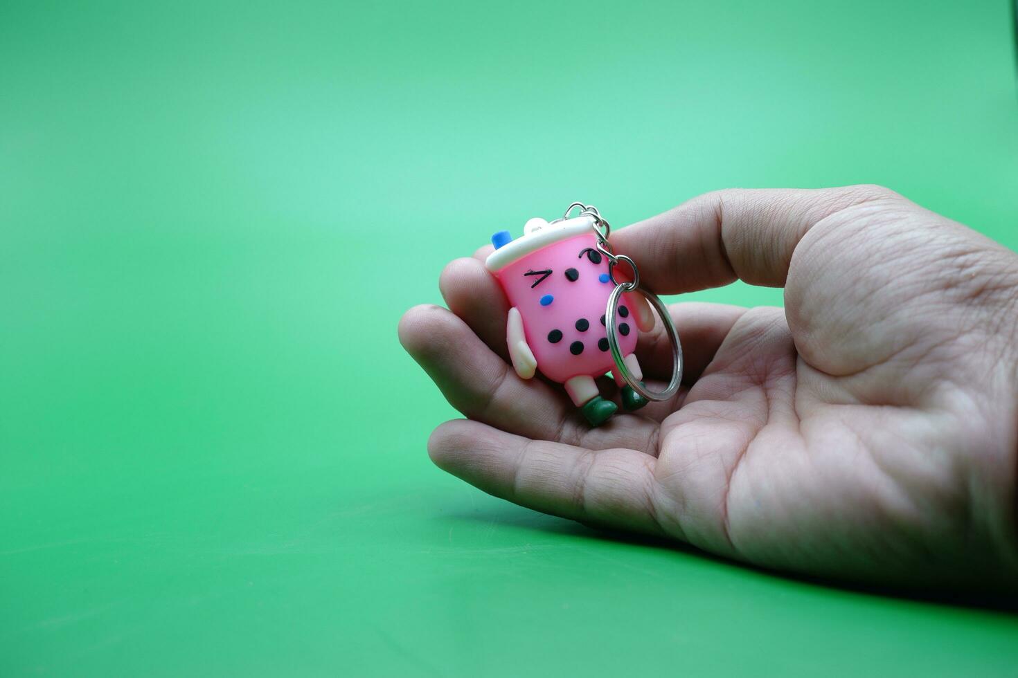 mano Tenere un' carino chiave catena su un' verde sfondo foto