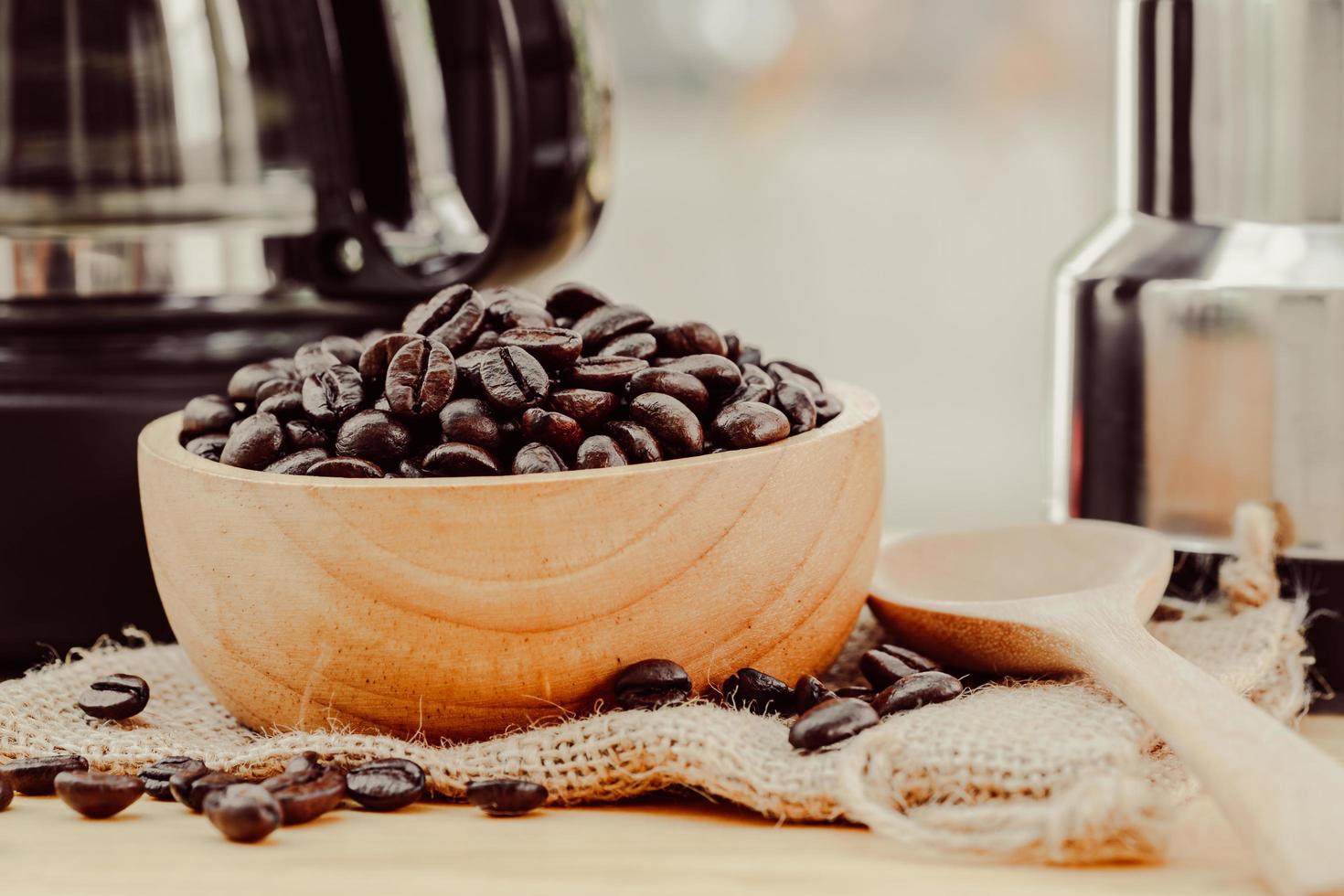 chicco di caffè su una ciotola di legno con sfondo di caffè fatto in casa foto