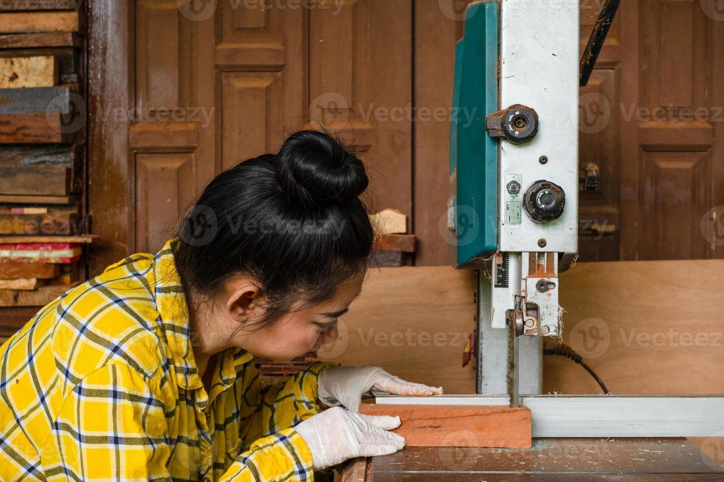 le donne in piedi stanno lavorando artigianalmente il legno tagliato su un banco da lavoro foto