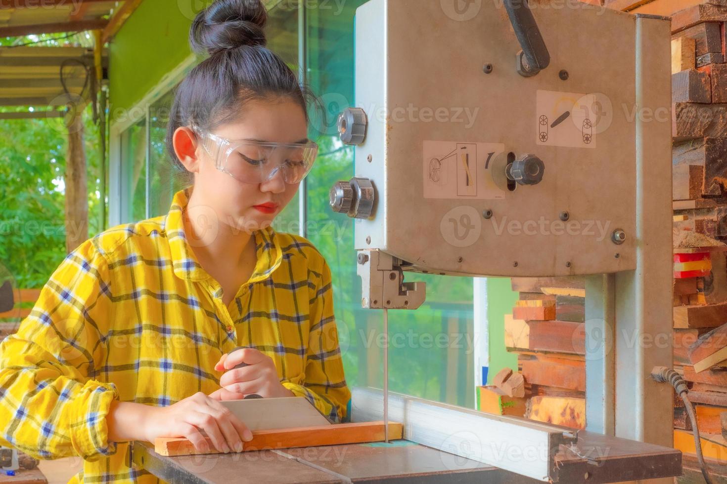 le donne in piedi stanno lavorando artigianalmente il legno tagliato su un banco da lavoro foto
