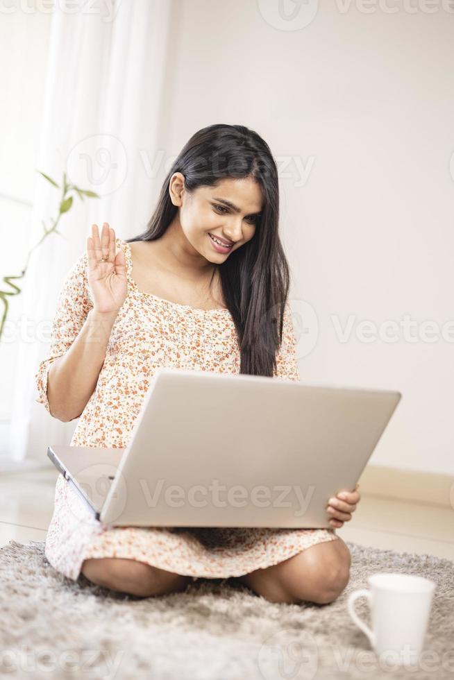 attraente giovane donna indiana che parla in videochiamata con il laptop foto