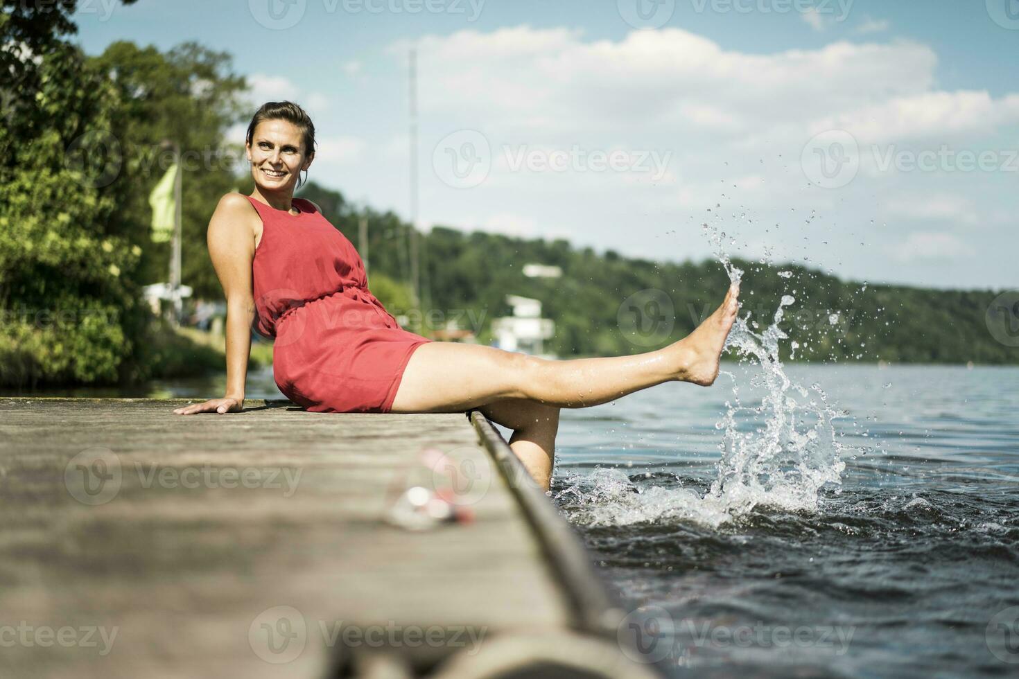 contento donna seduta su molo a un' lago foto