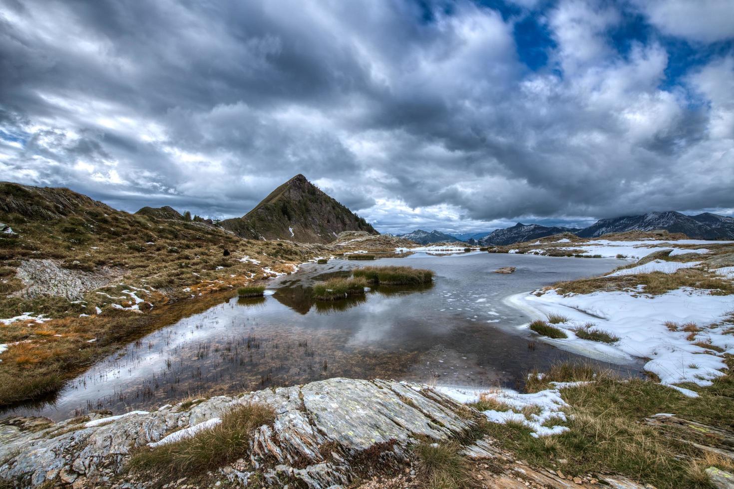 piccolo lago alpino con la prima neve sulle alpi italiane foto