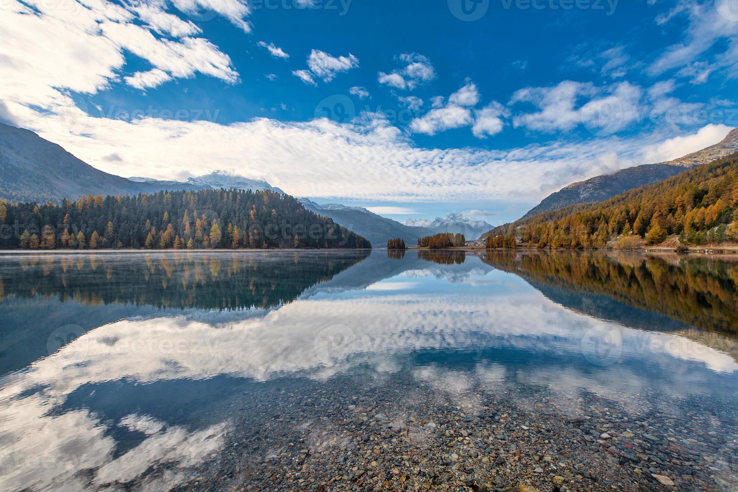 paesaggio di montagna con un lago dove si riflettono le nuvole foto